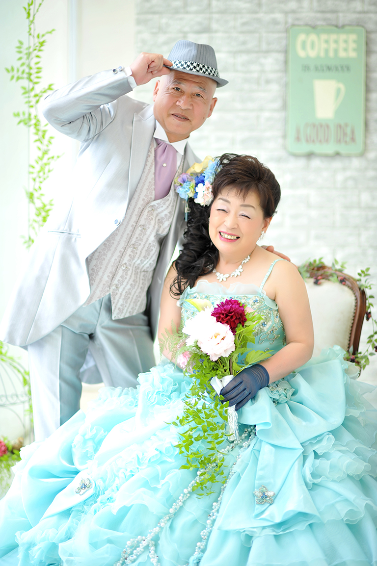 水色のドレスと白のタキシード姿の夫婦の写真